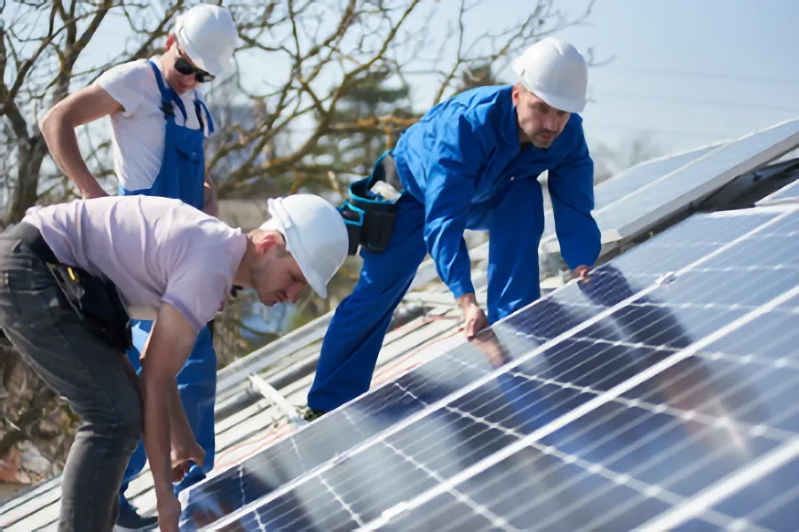 AdobeStock_247218908 Monteure beim Installieren von PV-Modulen auf einem Dach