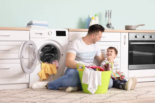 AdobeStock_348555216_ergebnis Mann mit Kind beim Wäsche waschen